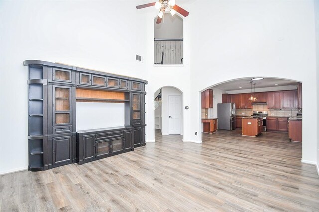 unfurnished living room with hardwood / wood-style flooring, ceiling fan, and a high ceiling