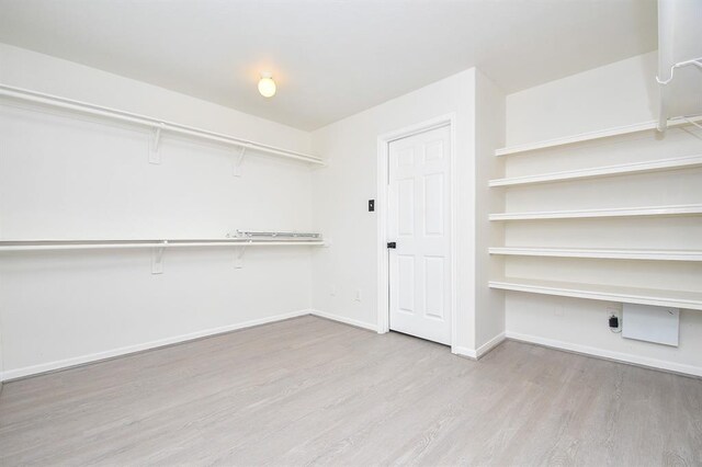 walk in closet with light hardwood / wood-style flooring