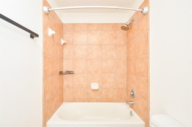 bathroom featuring tiled shower / bath and toilet