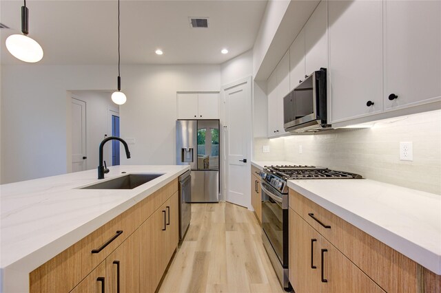 kitchen with white cabinets, decorative light fixtures, sink, and stainless steel appliances