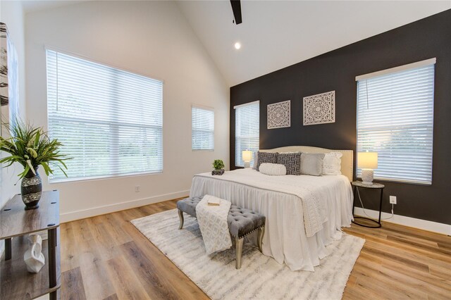 bedroom featuring high vaulted ceiling, light hardwood / wood-style flooring, multiple windows, and ceiling fan