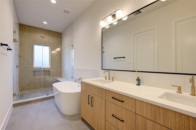 bathroom featuring tile patterned flooring, shower with separate bathtub, vanity, and tile walls