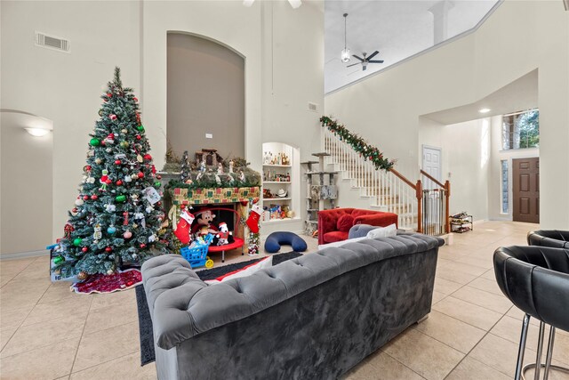 living room featuring ceiling fan, light tile patterned flooring, and a towering ceiling