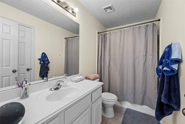 full bathroom featuring tile patterned flooring, a textured ceiling, toilet, shower / tub combo with curtain, and vanity