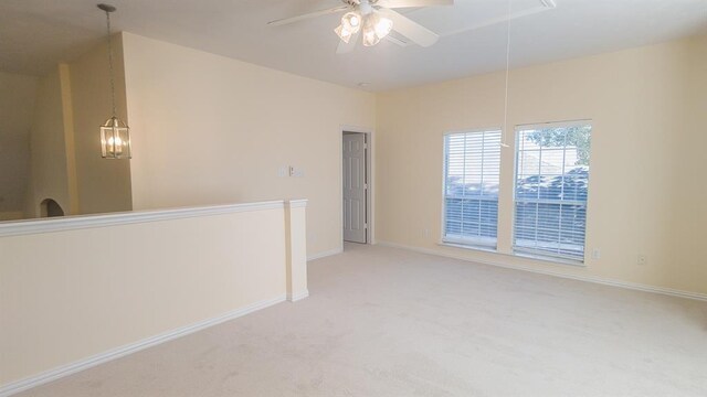 spare room with ceiling fan with notable chandelier and light colored carpet