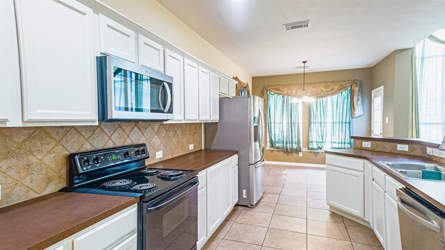 kitchen featuring stainless steel appliances, a notable chandelier, pendant lighting, decorative backsplash, and white cabinets