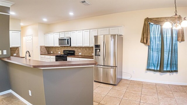 kitchen with white cabinets, appliances with stainless steel finishes, kitchen peninsula, and decorative light fixtures