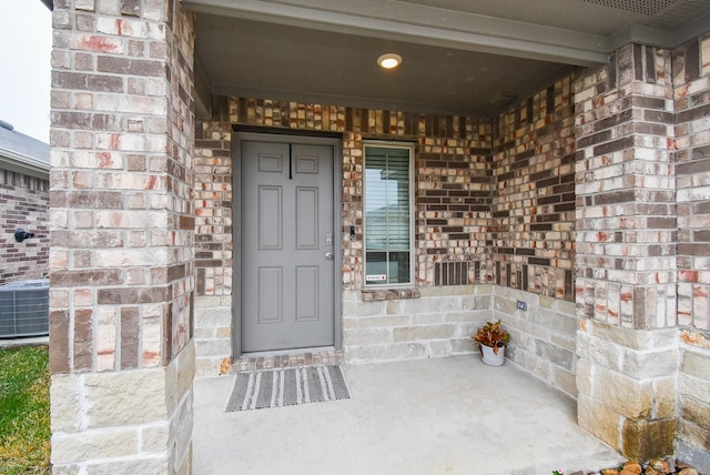 view of exterior entry with covered porch and cooling unit