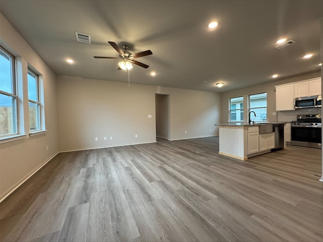 kitchen with stainless steel appliances, a ceiling fan, visible vents, white cabinets, and open floor plan