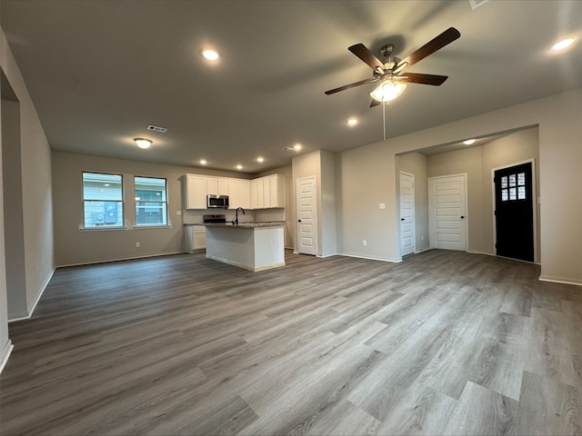 unfurnished living room featuring a sink, ceiling fan, baseboards, and plenty of natural light