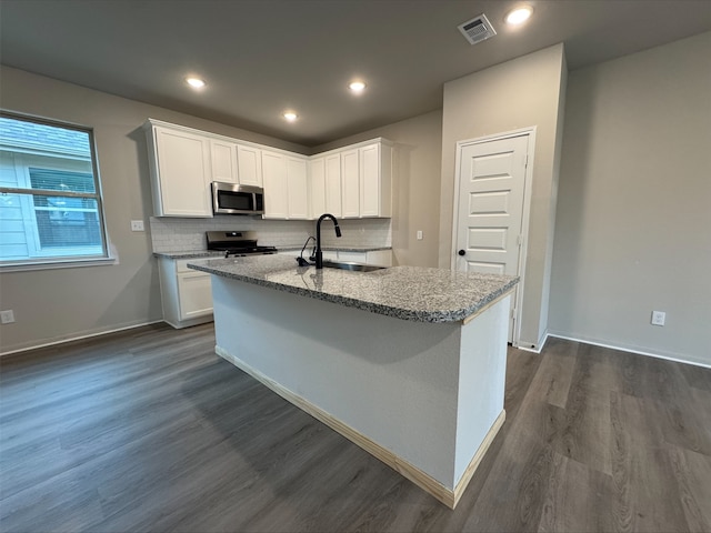 kitchen with a sink, visible vents, stainless steel appliances, light stone countertops, and dark wood finished floors