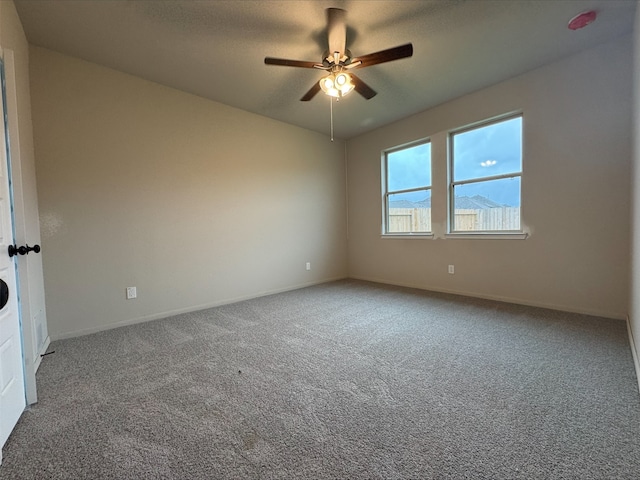 carpeted empty room featuring baseboards and a ceiling fan