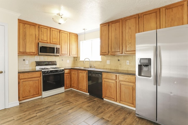 kitchen with stainless steel appliances, crown molding, sink, wood-type flooring, and decorative light fixtures