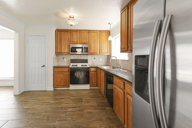 kitchen with decorative light fixtures, crown molding, sink, and appliances with stainless steel finishes