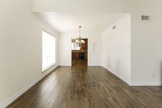 unfurnished room with an inviting chandelier, sink, ornamental molding, a textured ceiling, and dark hardwood / wood-style flooring