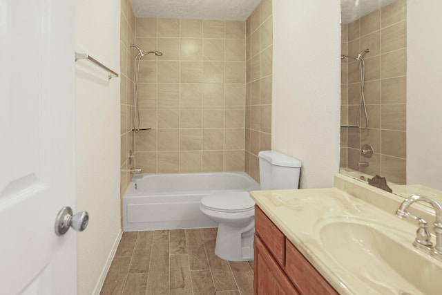 full bathroom with vanity, toilet, a textured ceiling, and tiled shower / bath combo