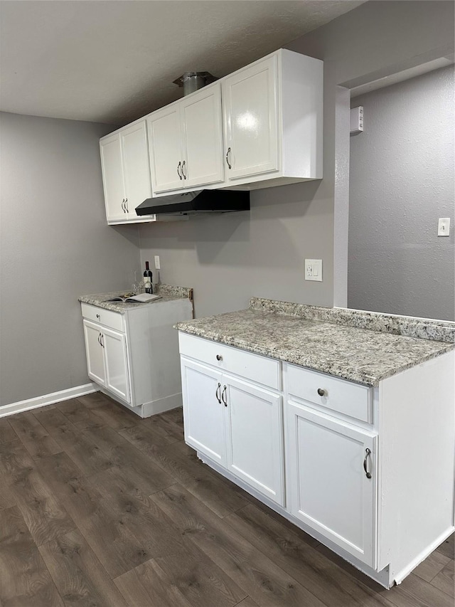 kitchen featuring light stone countertops, dark hardwood / wood-style flooring, and white cabinetry