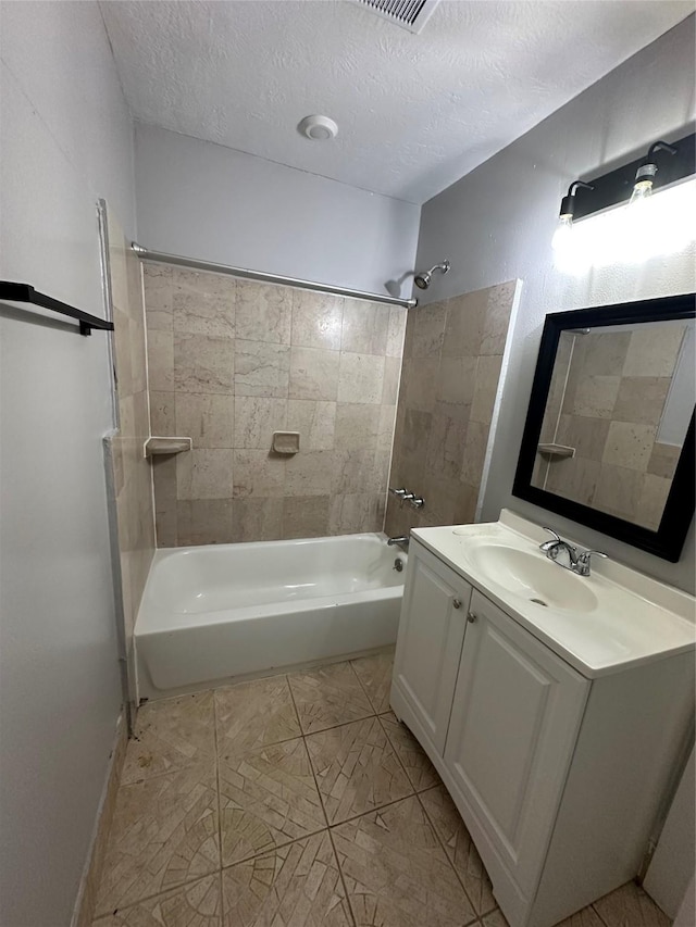 bathroom featuring vanity, a textured ceiling, and tiled shower / bath