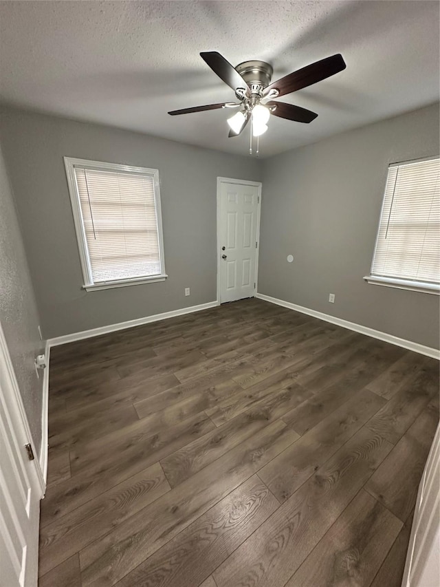 unfurnished room featuring plenty of natural light, ceiling fan, and dark hardwood / wood-style floors