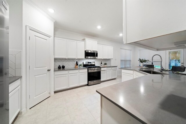 kitchen with sink, stainless steel appliances, decorative backsplash, white cabinets, and ornamental molding