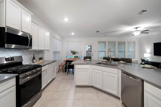 kitchen with appliances with stainless steel finishes, backsplash, crown molding, sink, and white cabinets