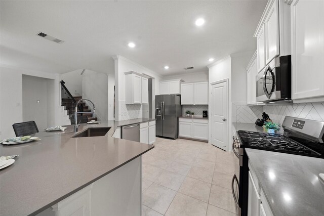 kitchen featuring sink, stainless steel appliances, light tile patterned floors, crown molding, and white cabinets