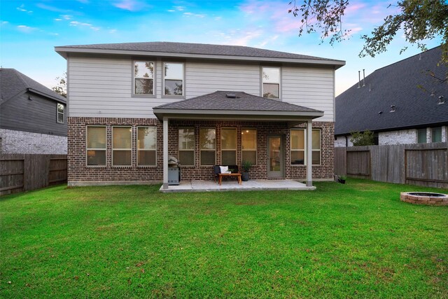 rear view of property with a fire pit, a patio, and a lawn