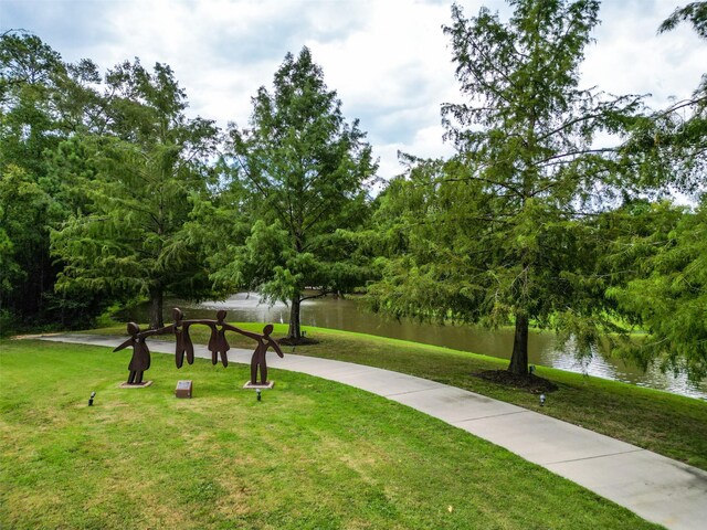 view of home's community with a water view and a lawn