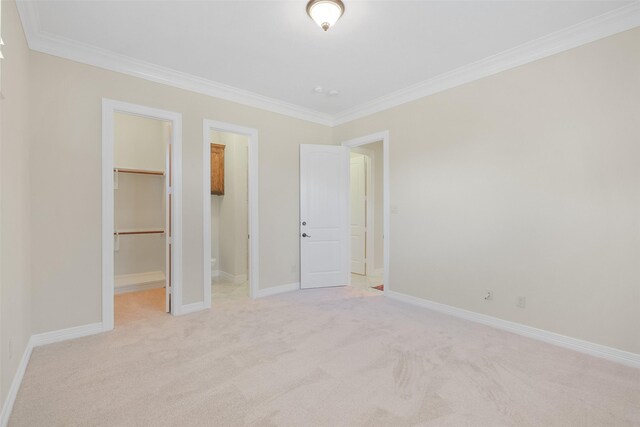 unfurnished bedroom featuring a walk in closet, light colored carpet, a closet, and ornamental molding