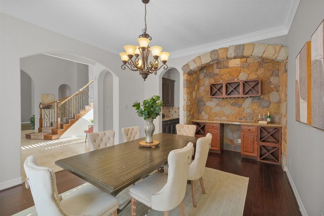 dining area featuring a chandelier, dark wood-type flooring, and ornamental molding