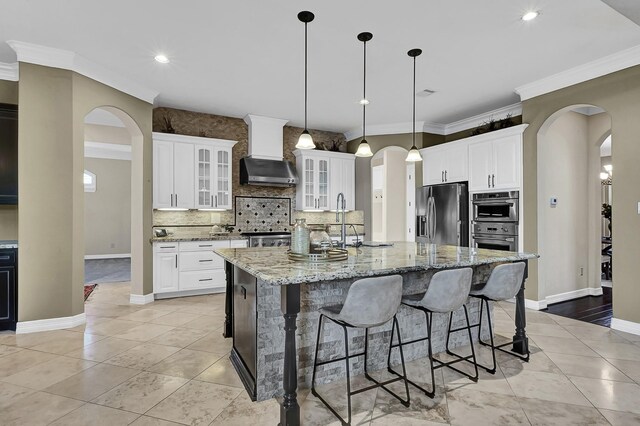 kitchen with a center island with sink, white cabinets, wall chimney range hood, and stainless steel appliances