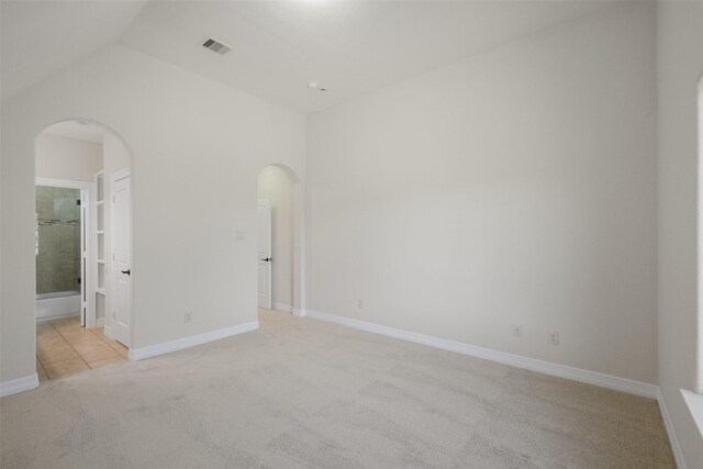 spare room with light carpet and vaulted ceiling