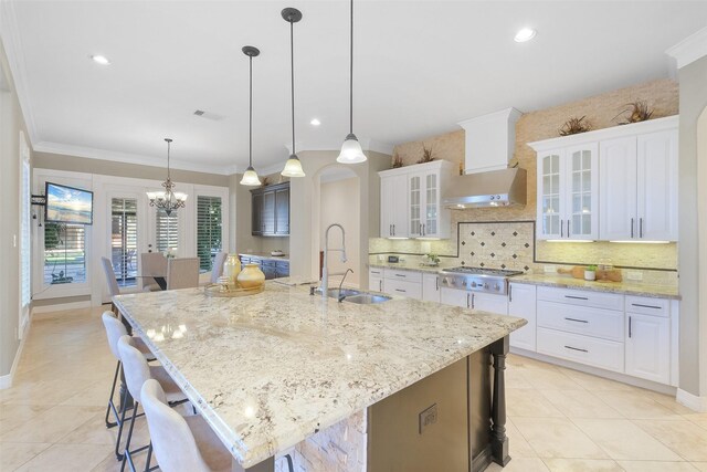 kitchen featuring white cabinetry, sink, and a large island with sink