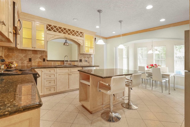 kitchen featuring pendant lighting, sink, ornamental molding, tasteful backsplash, and a kitchen island