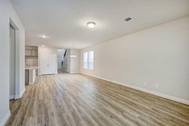 unfurnished living room featuring light hardwood / wood-style flooring and a chandelier