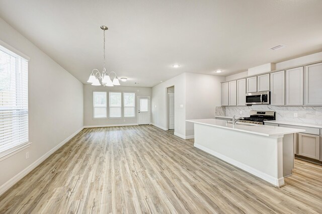 kitchen featuring tasteful backsplash, gray cabinetry, stainless steel appliances, decorative light fixtures, and a notable chandelier