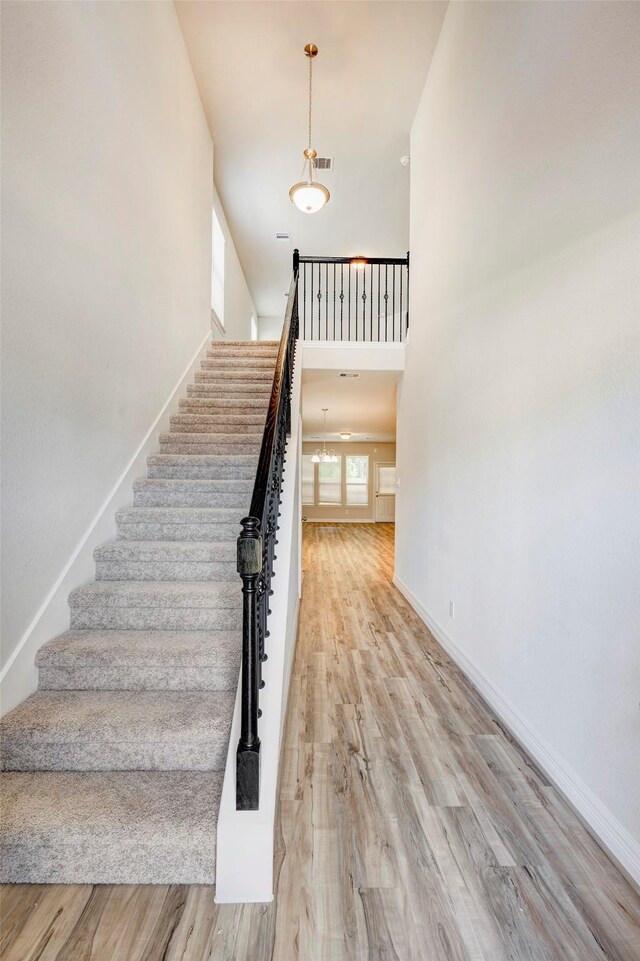 stairway with wood-type flooring and a high ceiling