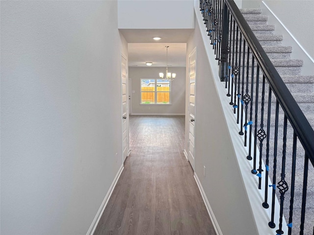 hall with hardwood / wood-style floors and a chandelier