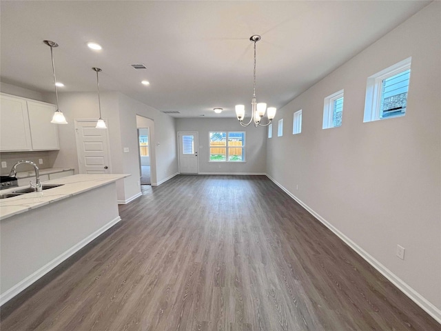 unfurnished dining area featuring dark wood-type flooring, a chandelier, and sink