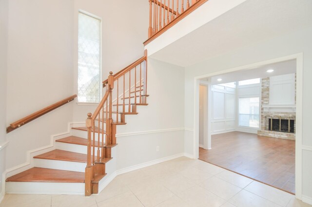 stairway featuring tile patterned flooring, a healthy amount of sunlight, and a fireplace