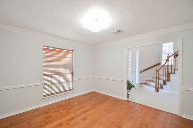 spare room featuring a textured ceiling, light hardwood / wood-style floors, and crown molding