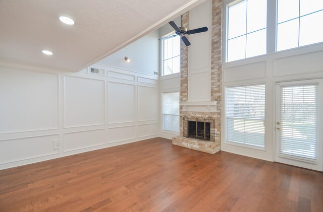 unfurnished living room with hardwood / wood-style flooring, ceiling fan, plenty of natural light, and a high ceiling