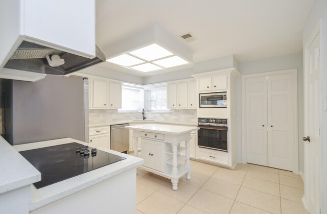 kitchen featuring sink, black appliances, light tile patterned floors, white cabinets, and a kitchen island