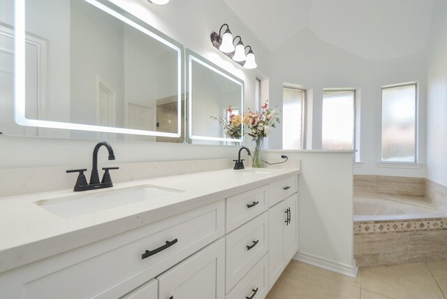 bathroom with tile patterned floors, tiled tub, vanity, and vaulted ceiling