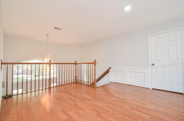 empty room with light hardwood / wood-style flooring and a chandelier