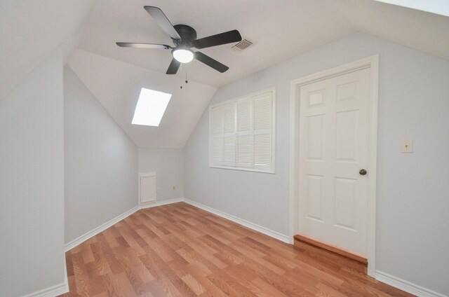 additional living space featuring light hardwood / wood-style floors, ceiling fan, and vaulted ceiling with skylight