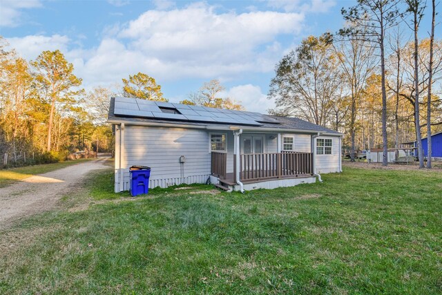 back of property featuring a lawn and solar panels