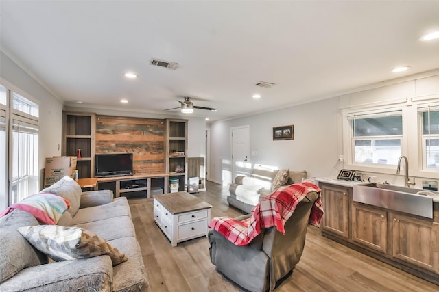 living room featuring light wood-type flooring, ceiling fan, plenty of natural light, and sink