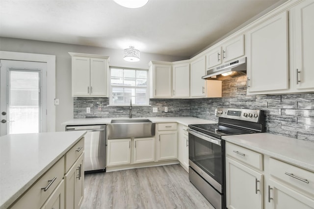 kitchen featuring white cabinetry, appliances with stainless steel finishes, backsplash, light hardwood / wood-style flooring, and sink