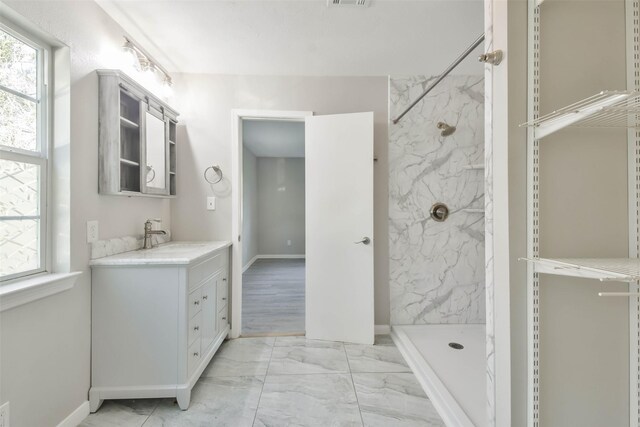 bathroom with tiled shower and vanity